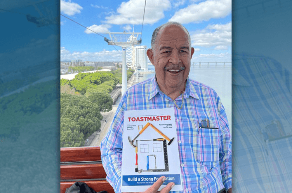 Man holding Toastmaster magazine in Portugal with water in background