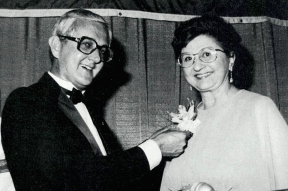Black and white photo of man pinning flower on woman’s dress